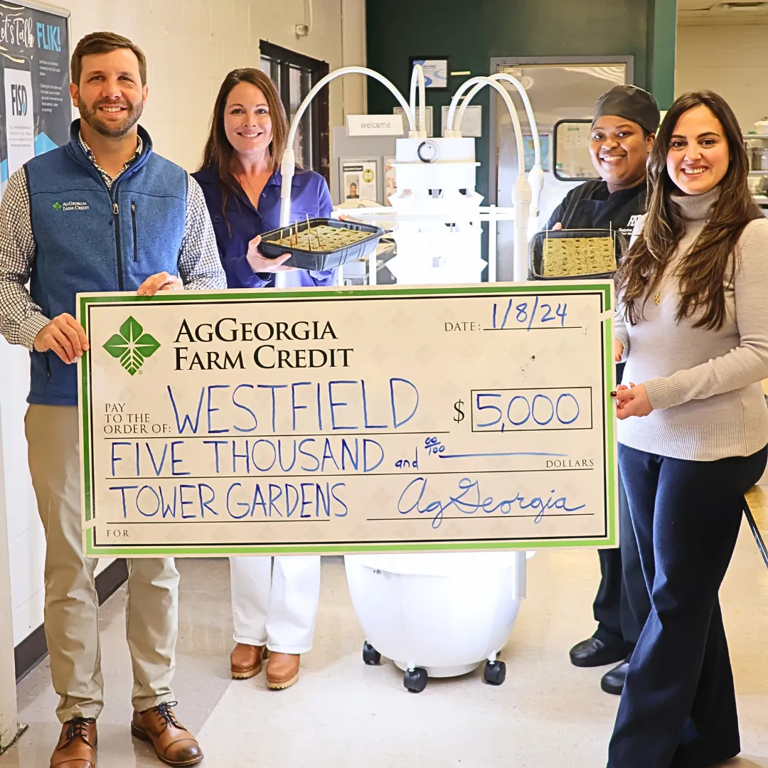Group of people smiling and holding a big check.