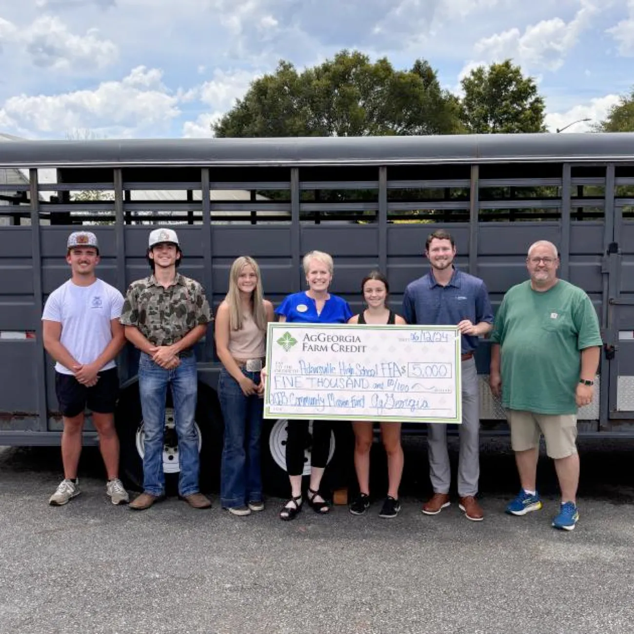 Group of people smiling and holding a big check.