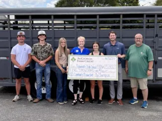 A group of people smiling, holding an oversized check.